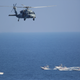 A U.S. Navy MH-60 Seahawk helicopter flies near Iranian Revolutionary Guards Corps Navy patrol boats. Note machine guns and other support weapons mounted on the bow. 2018.